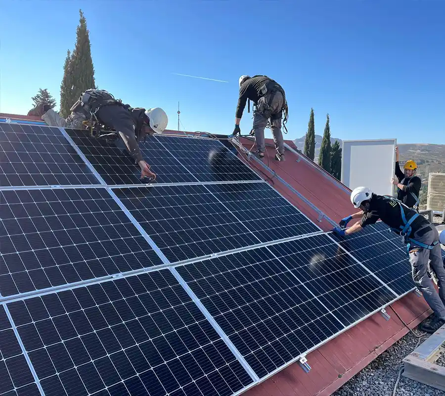 Equipo de profesionales instalando placas solares en superficie inclinada